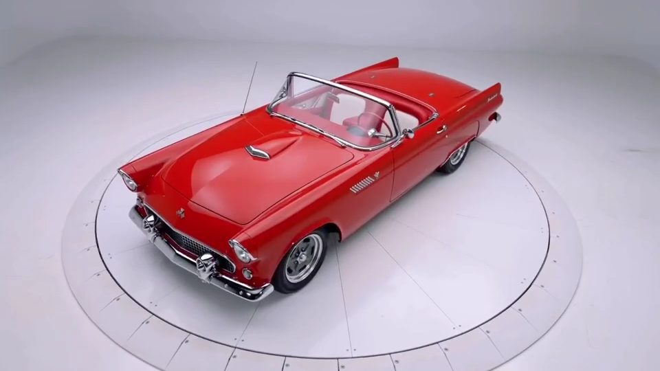 Elevated view of the cherry red 1955 Ford Thunderbird on a white studio turntable, top down, showing the full body.