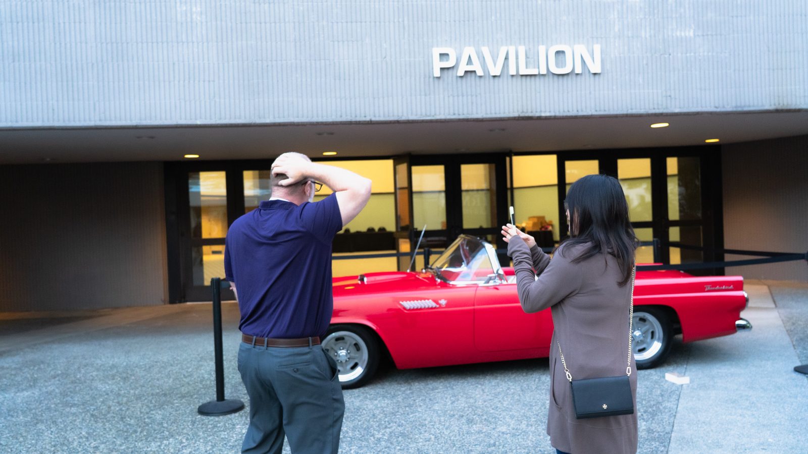 The winner stands with a hand on his head, taking in the Thunderbird parked outside the Pavilion.