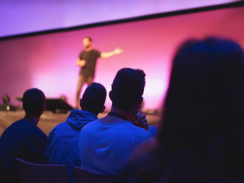 Speaker giving conference speech to audience at public event - Focus on right man back